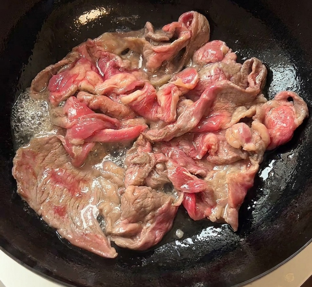 フライパンから焼き色のついた牛肉をお皿に移す様子。
