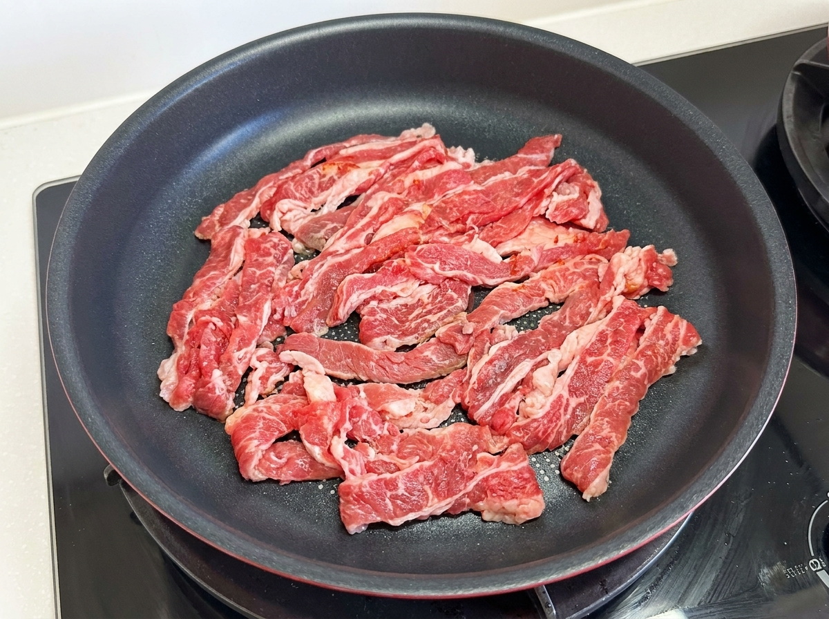 フライパンに牛バラ肉を広げて焼く様子