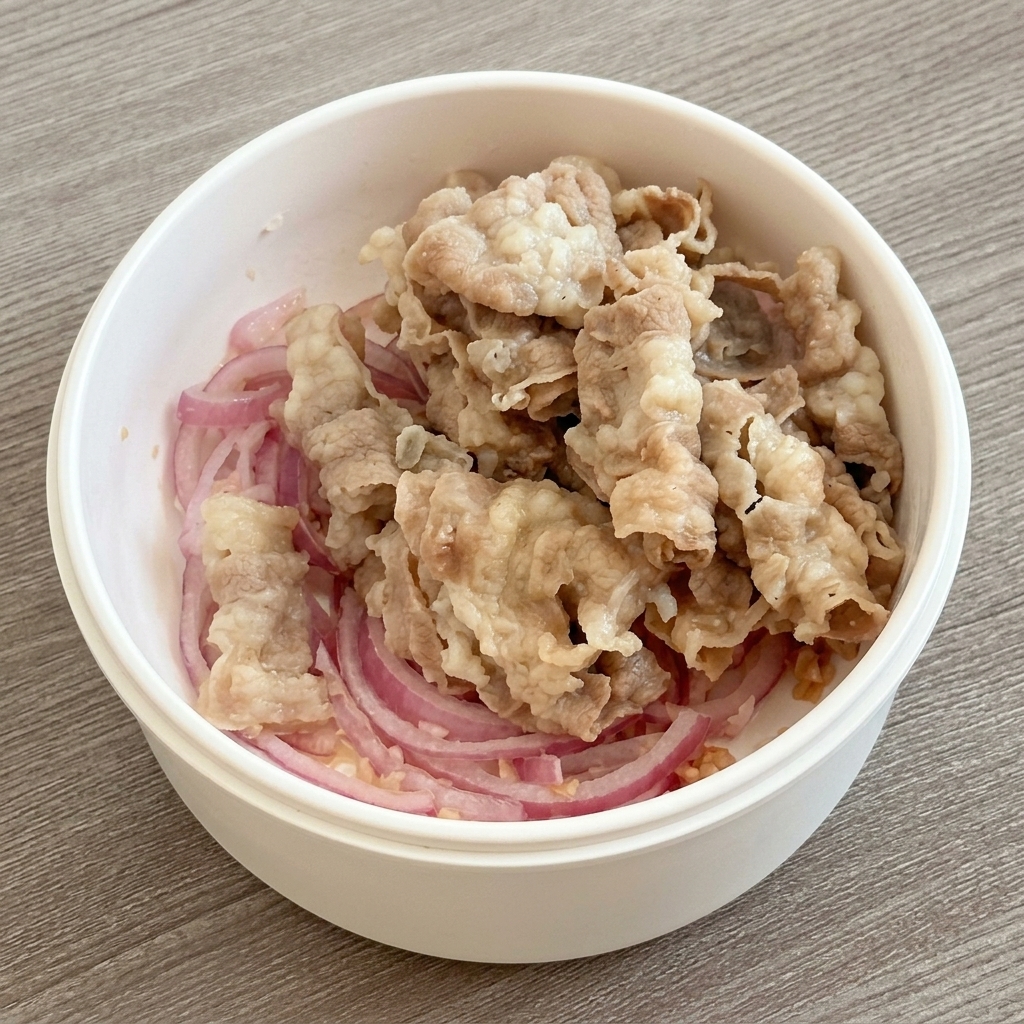 炒めた野菜の上に湯通しした牛肉を乗せる様子