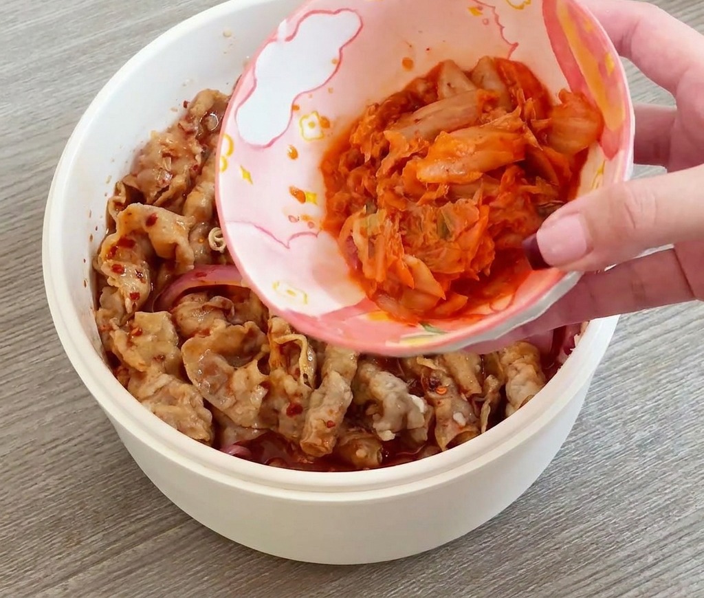 炒めた牛肉に刻みキムチを投入する様子