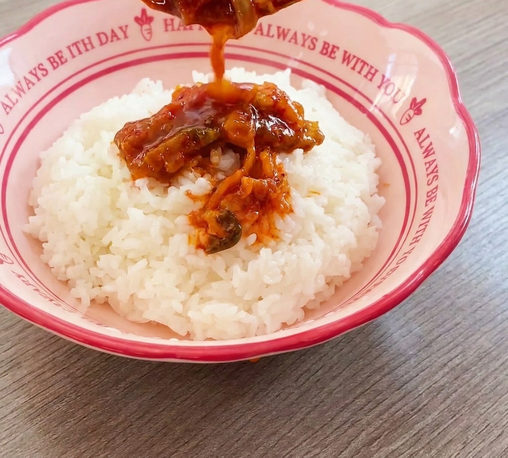 どんぶりの白米の上に具材を乗せる様子