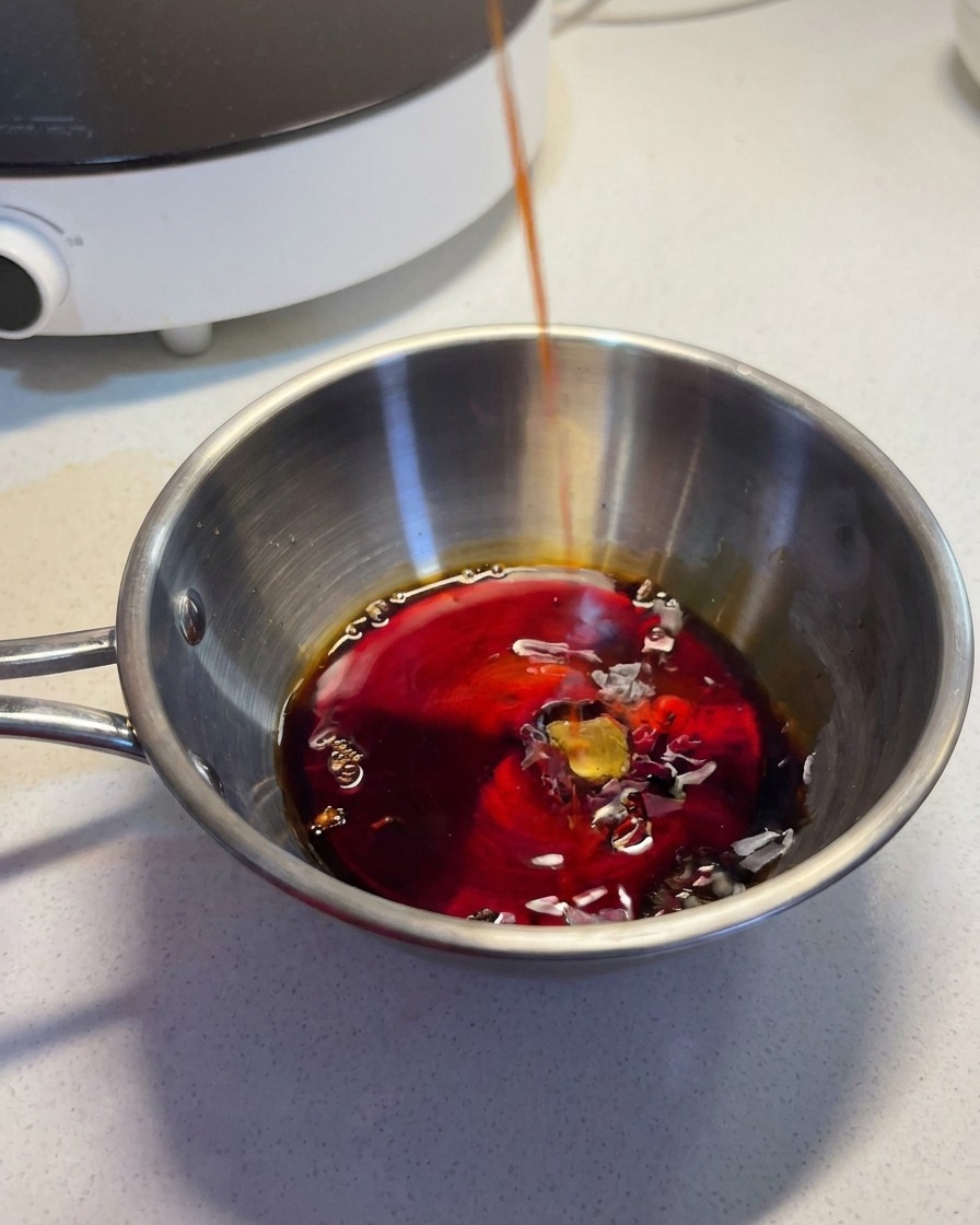 ステンレスのボウルに、醤油や酒などの調味料を注ぎ入れて混ぜ合わせている様子。