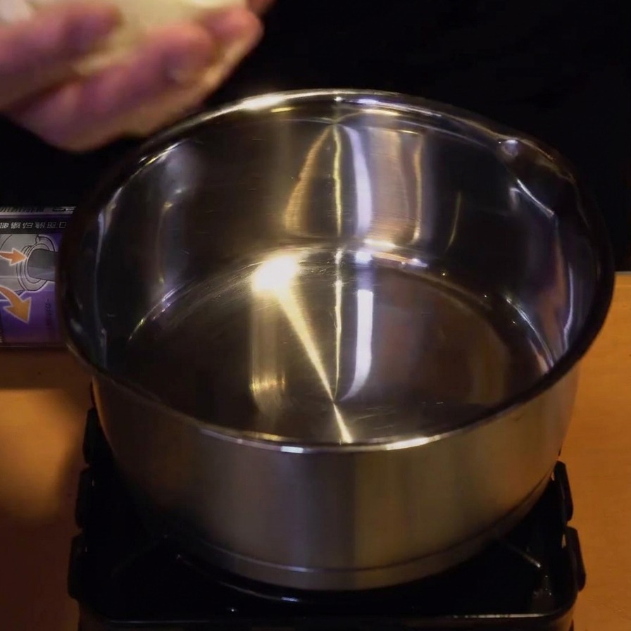コンロの上のステンレス製の小鍋に、切った玉ねぎと鶏肉を入れている様子。