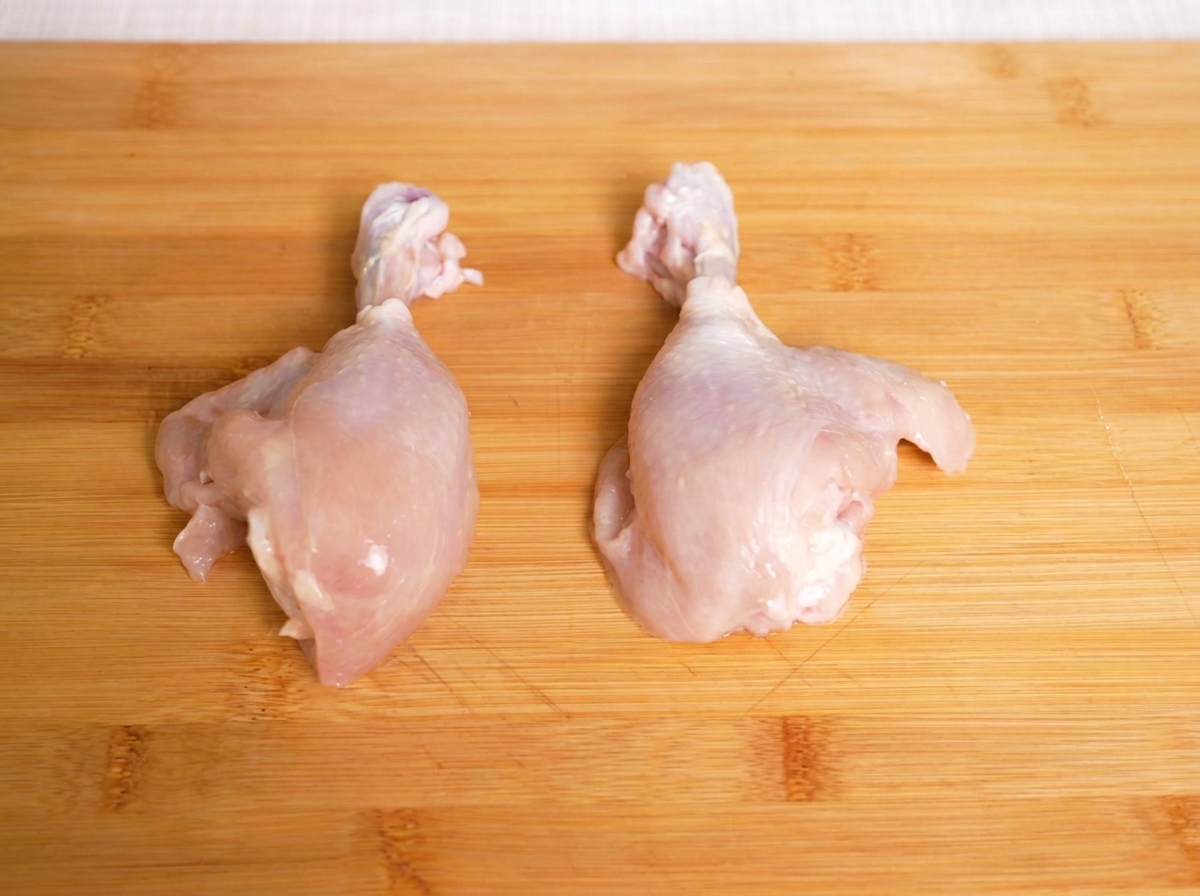 まな板の上に置かれた、切る前の生の鶏肉