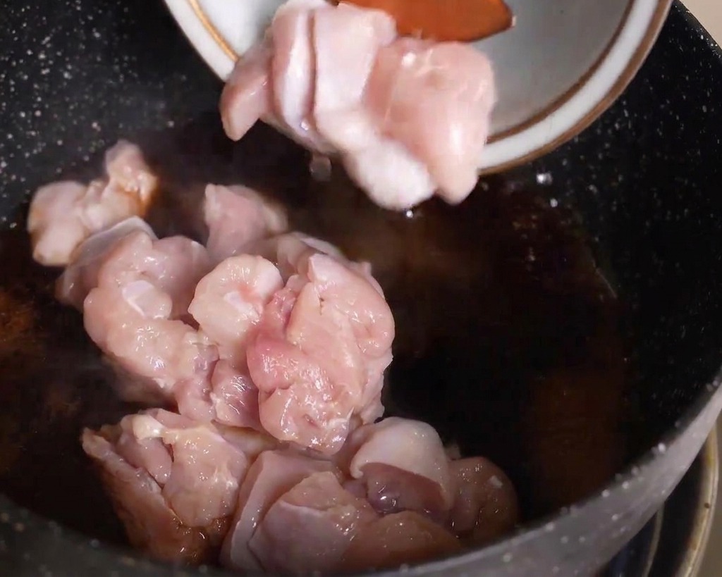 薄切りにした生の鶏肉を、煮立っている鍋のつゆの中に入れている様子
