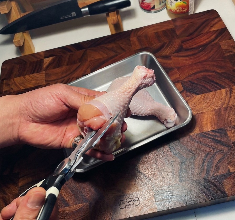 キッチングハサミで生の鶏もも肉の骨を外している様子。