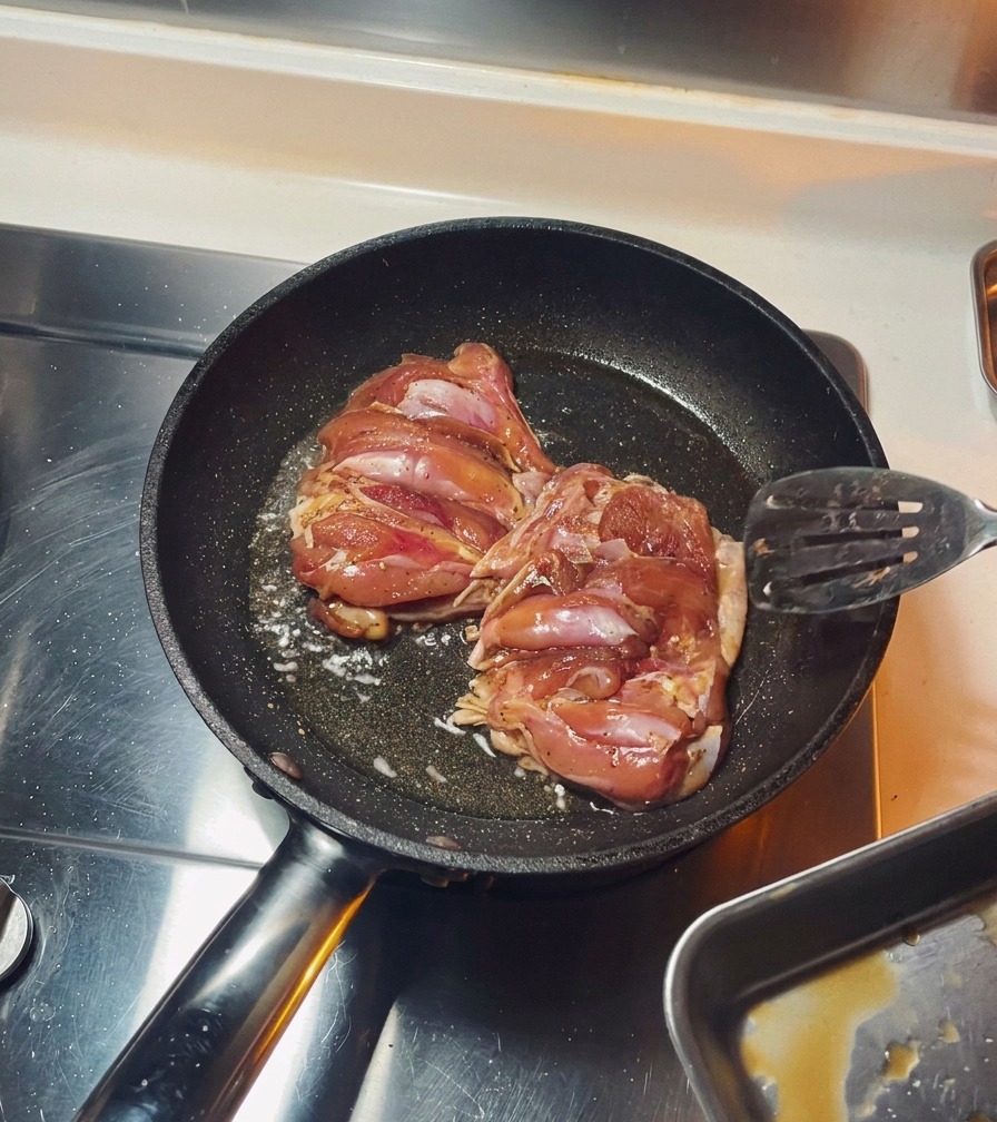 フライパンで皮目を下にして鶏肉を焼いている様子。