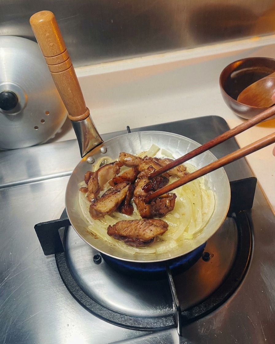玉ねぎの上に焼いた鶏肉を並べている様子。