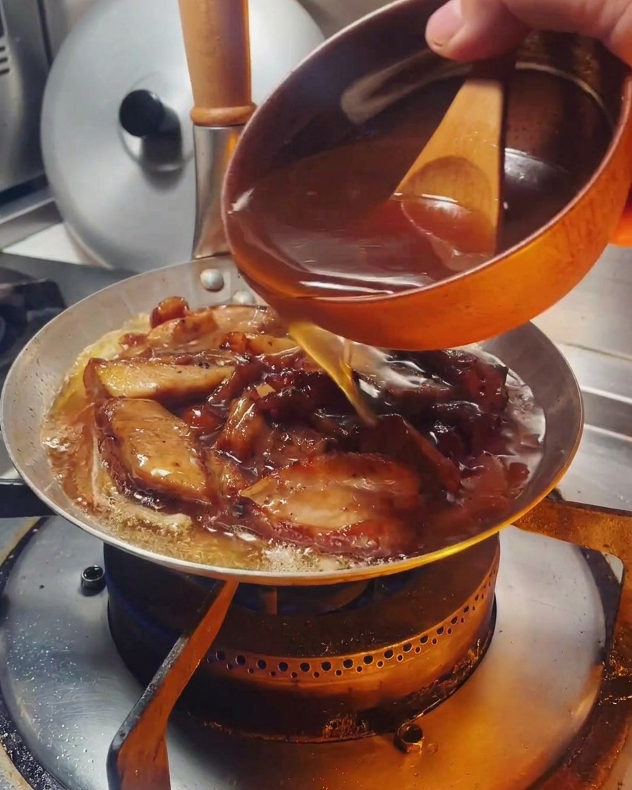 鶏肉と玉ねぎの入った鍋にタレを注いでいる様子。