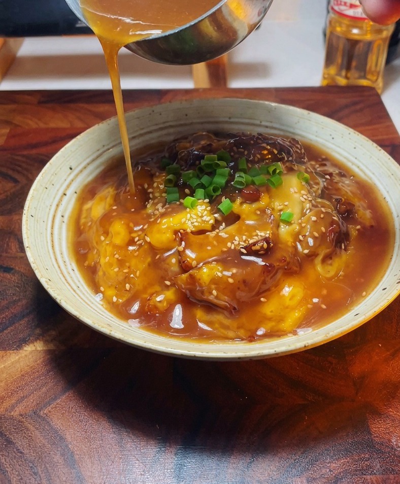 盛り付けた親子丼に、お玉で残りのタレをかけている様子。