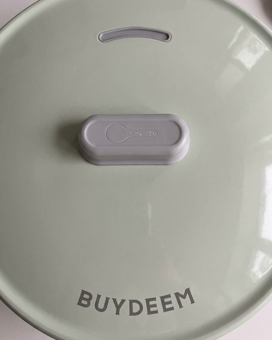 パステルグリーンの炊飯器の蓋を閉めて、調理を開始する様子。