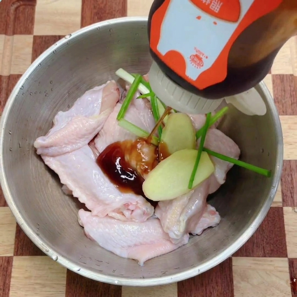 刻んだ薬味をのせた手羽中に、ボトルの照り焼きソースをかけている様子。