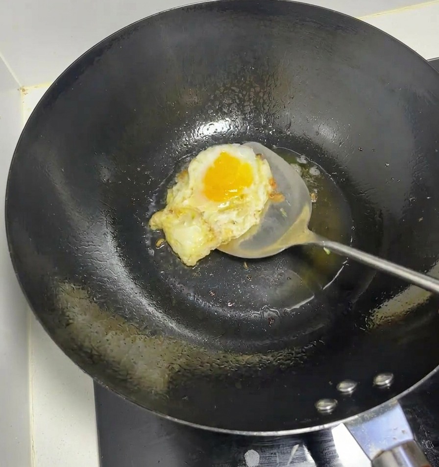 熱した中華鍋で、ヘラを使って卵を焼いている様子。