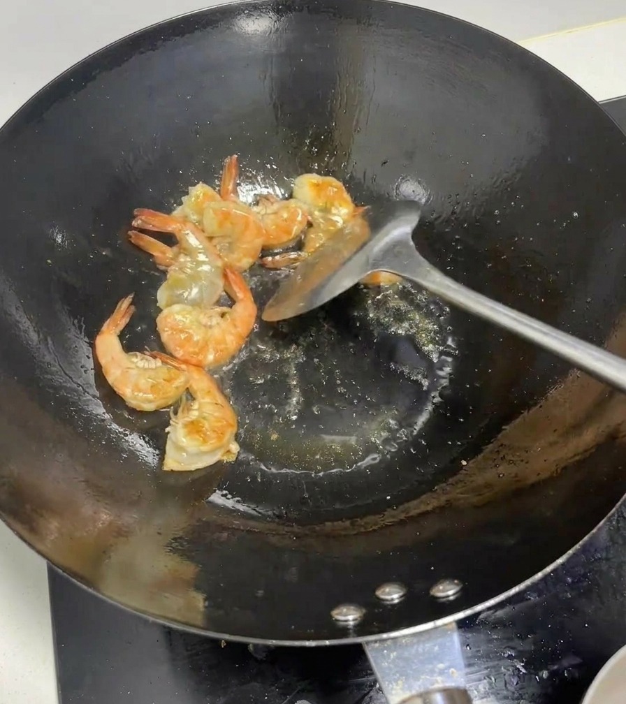 熱い鍋の中で、殻が鮮やかなピンク色に変わっていく海老の様子。