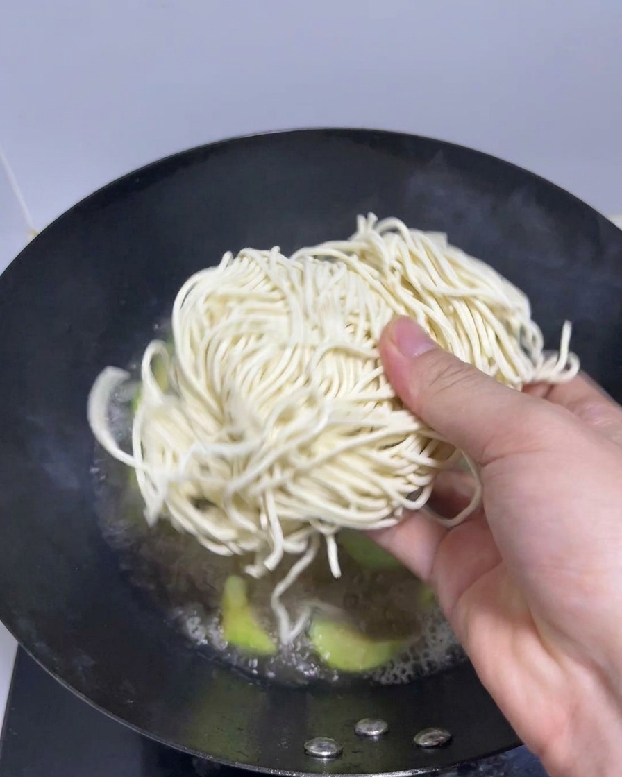 沸騰したスープが入った鍋に、生ラーメンの麺を投入している様子。
