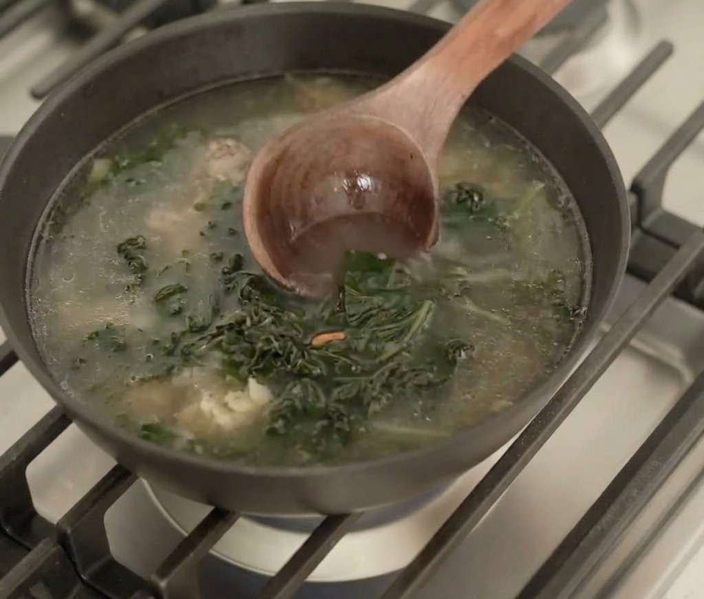 お玉でスープと具材をゆっくり混ぜ合わせる様子。