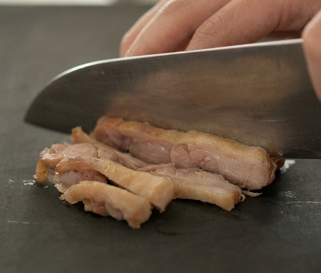 まな板の上で焼いた鴨肉を丁寧にスライスする様子。
