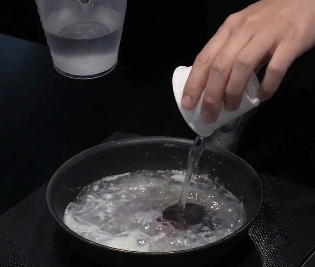 フライパンの中のルウに水を注ぎ、白い液体状に混ぜている様子