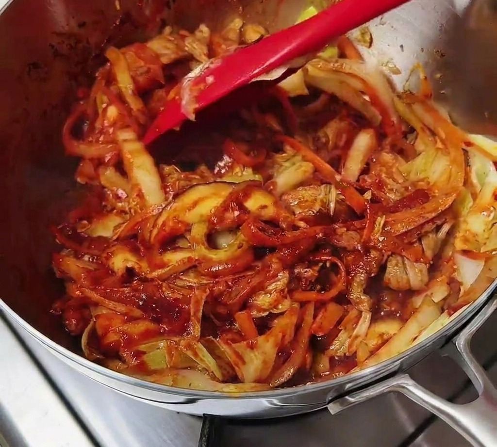 真っ赤なスパイスペーストが全体に絡んだ具材をヘラで炒めている様子。