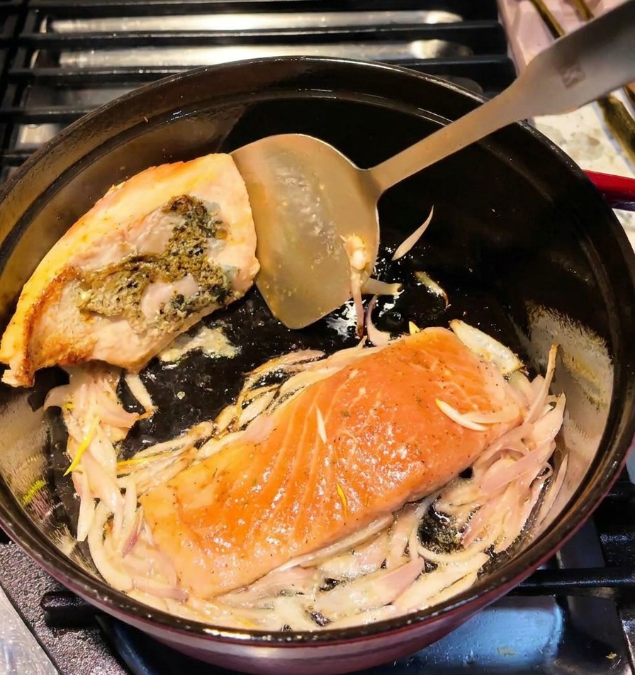 フライ返しで鮭を裏返し、表面にこんがりと焼き色がついている様子。