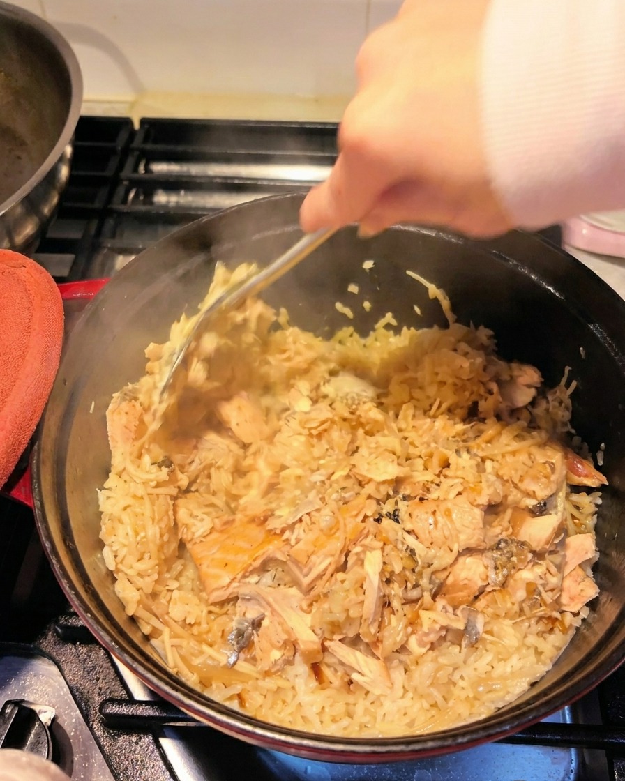 ヘラで鮭の身を大きくほぐしながら、ご飯と混ぜ合わせている様子。