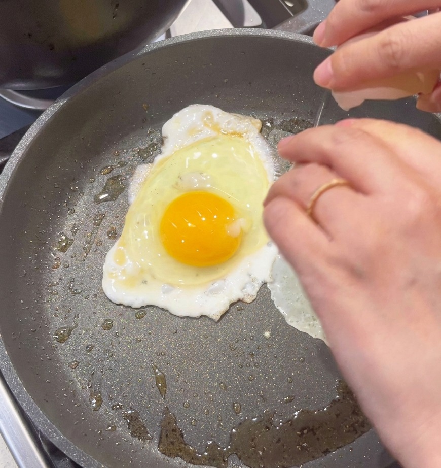 フライパンに卵を割り入れ、スクランブルエッグを作っている様子。