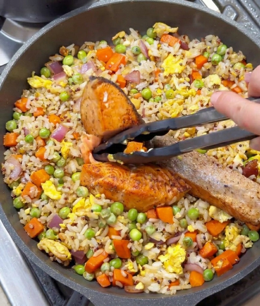 トングを使って焼いた鮭の身をチャーハンの上にのせている様子。