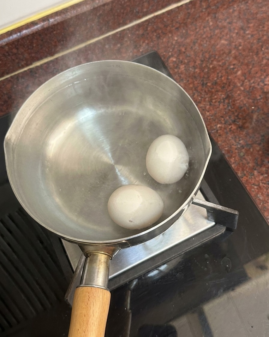 湯気が立ち上る鍋の底に沈んだ2つの白い卵。