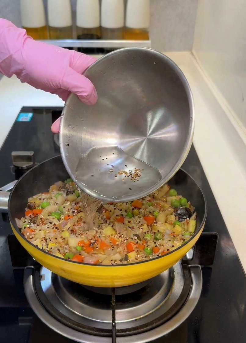 具材が入ったフライパンに水を注いでいる様子。