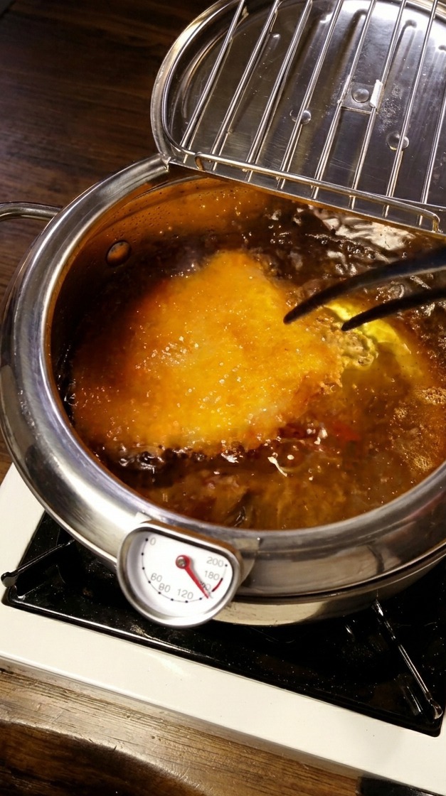 熱い油の中でトンカツを揚げている様子