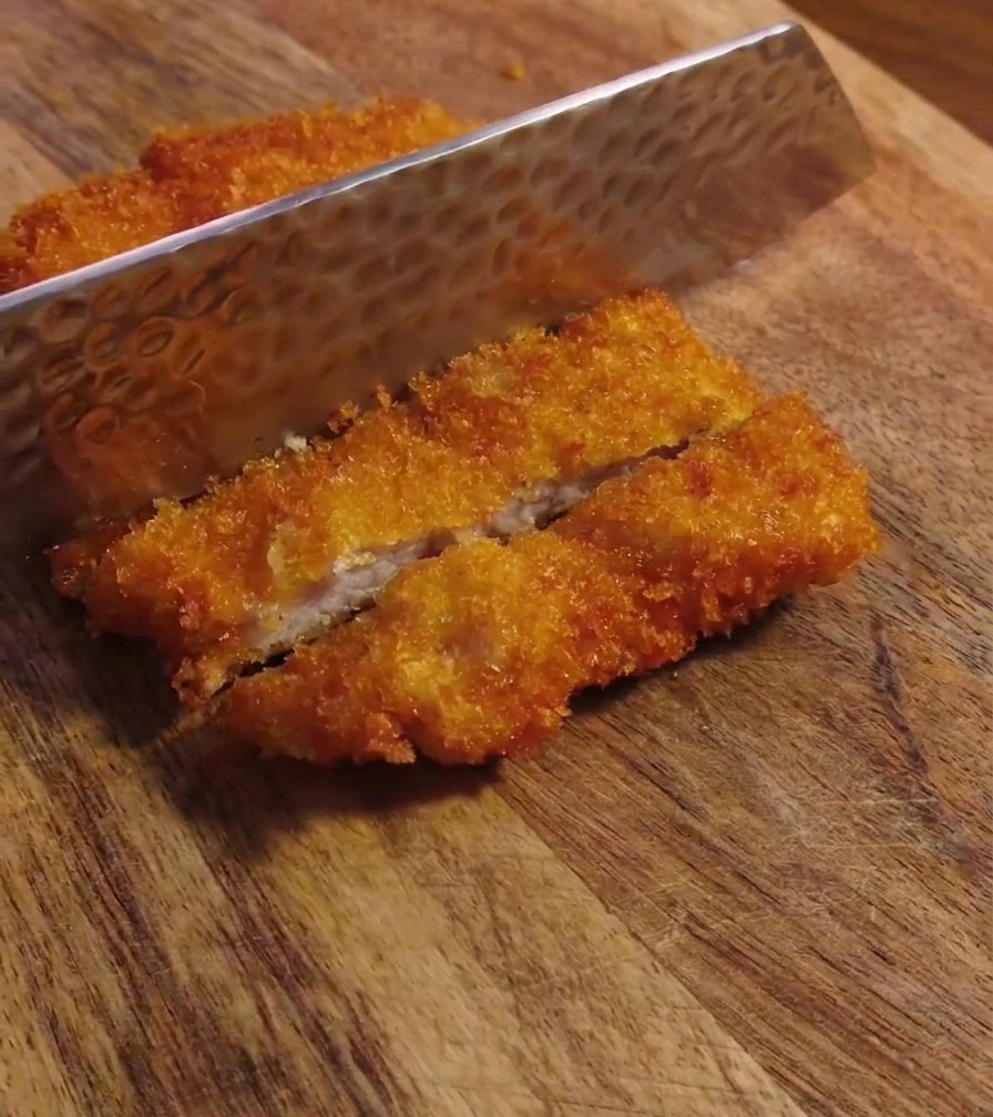 包丁でサクサクのトンカツを切り分けている様子