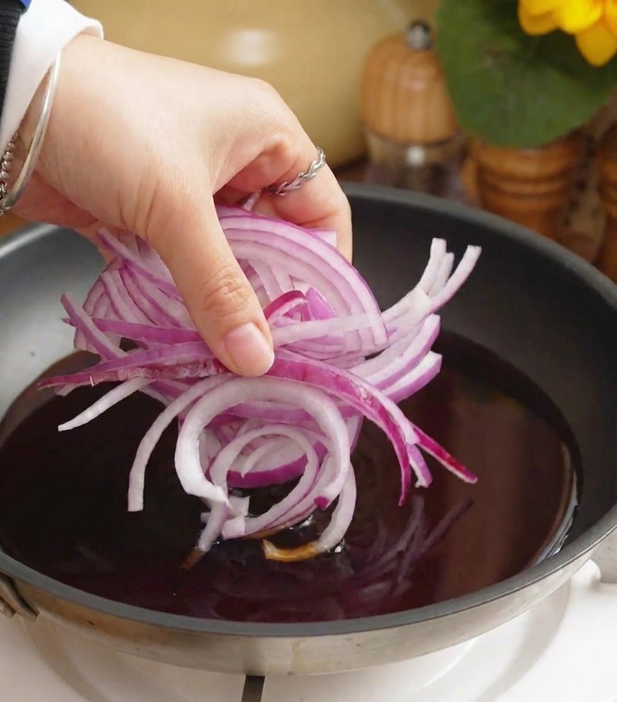 フライパンのタレで赤玉ねぎを煮込んでいる様子。