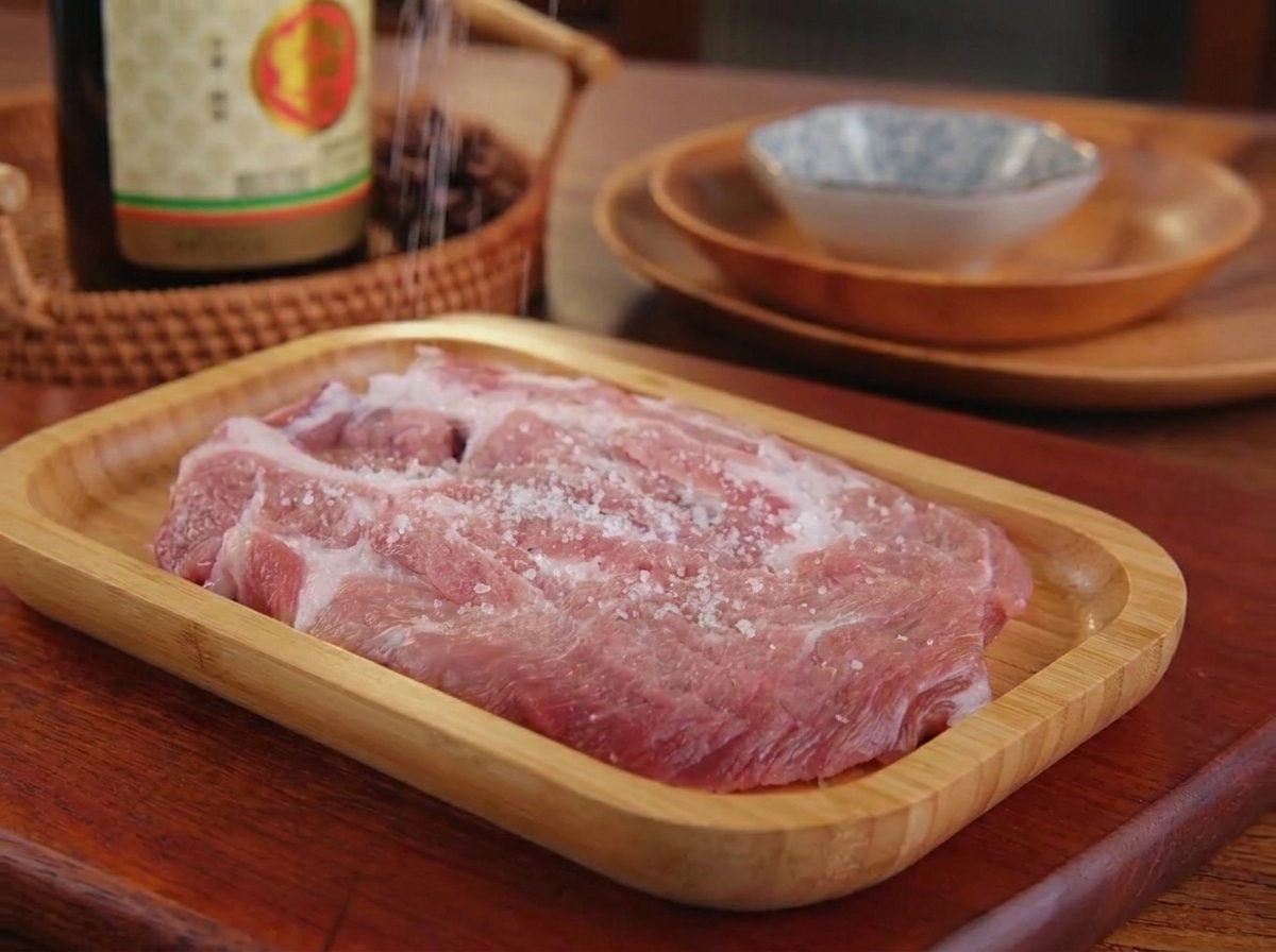 豚肉に塩と黒こしょうを振りかけて手で馴染ませている様子