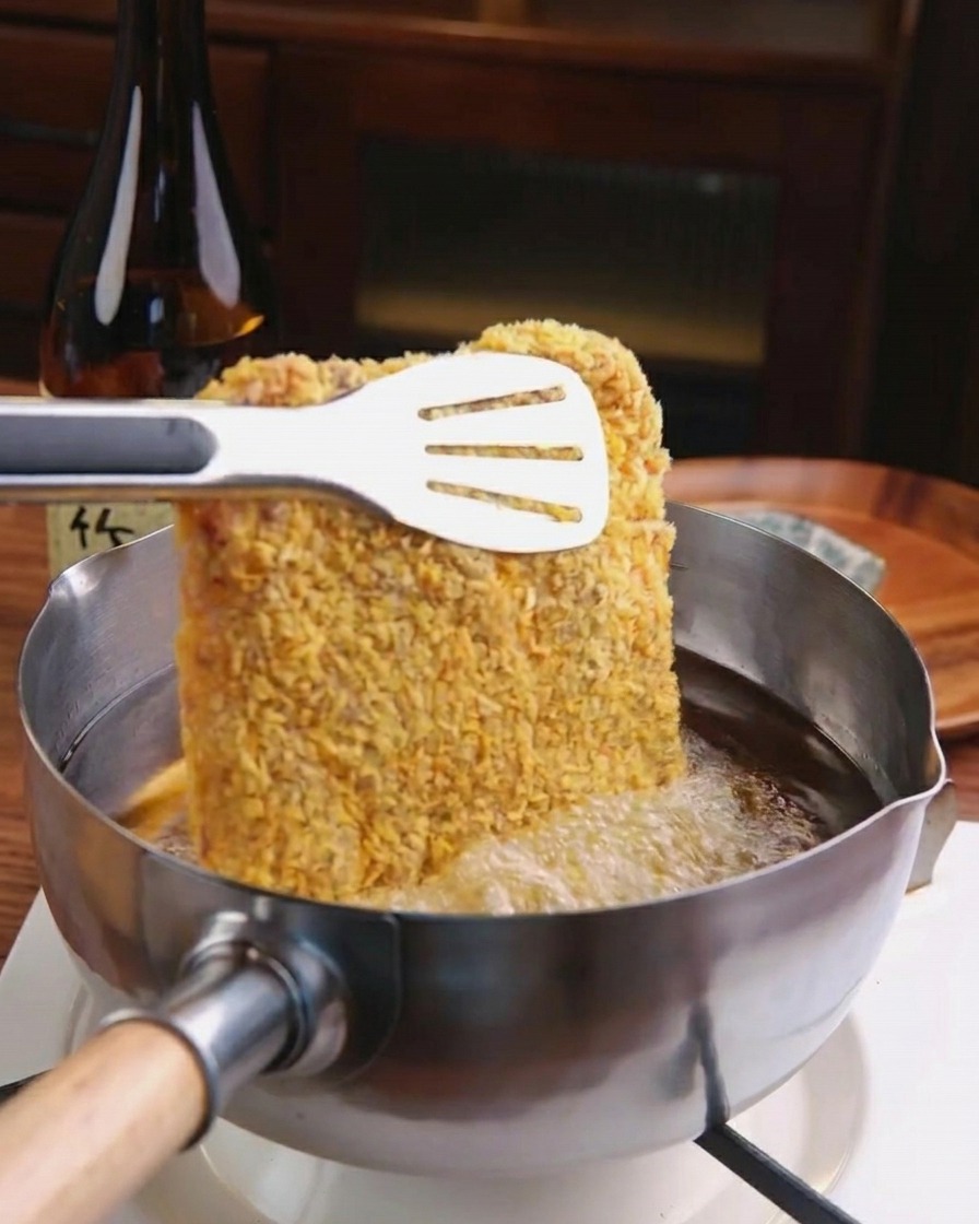 熱した油でトンカツがキツネ色に揚げられている様子