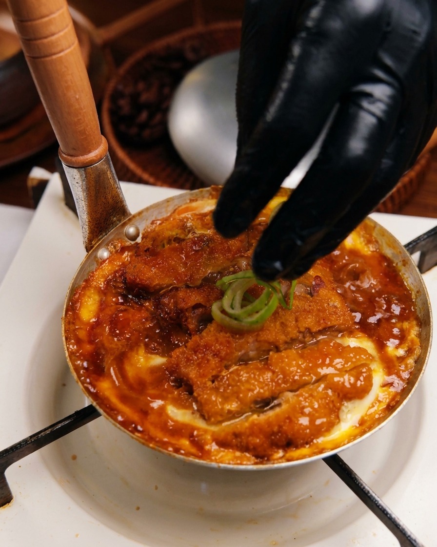 出来上がったカツ丼の上に、刻んだねぎを散らしている様子。