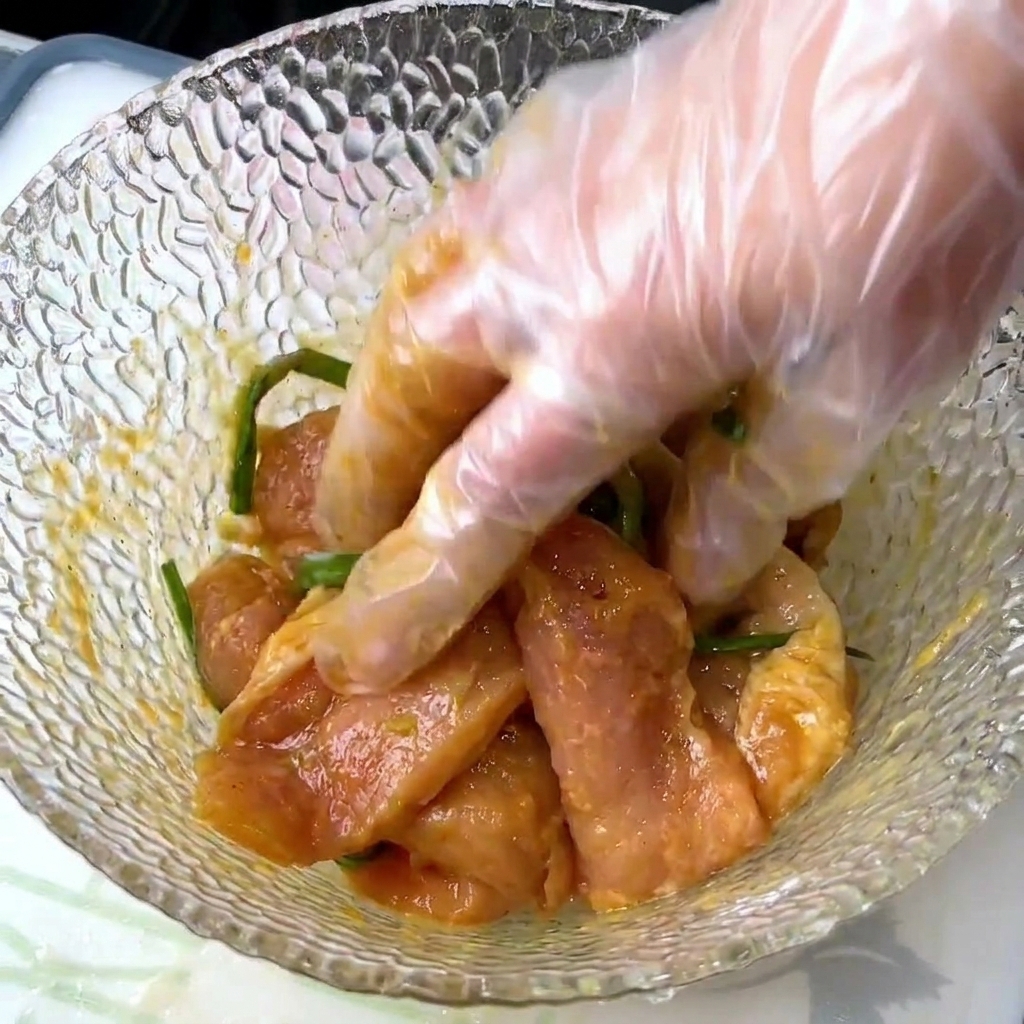調味料が均一に馴染むよう手で豚肉を揉み込んでいる工程