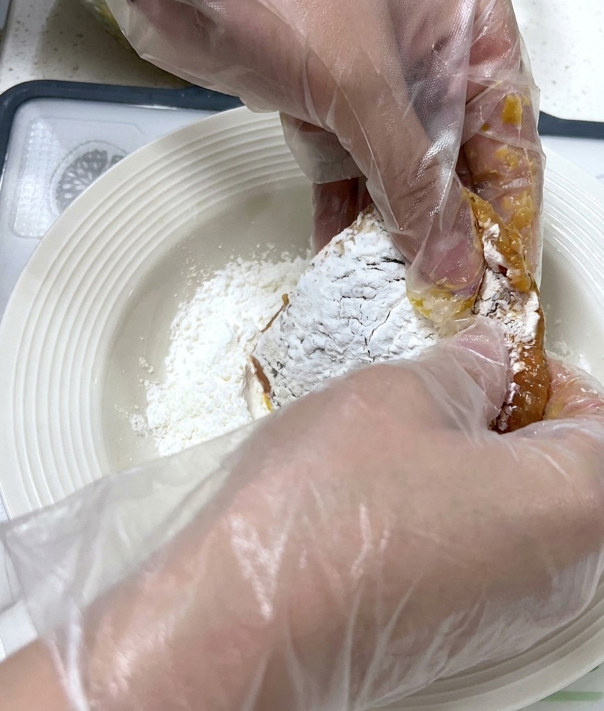 下味をつけた肉の両面に白い片栗粉を丁寧にまぶしている様子