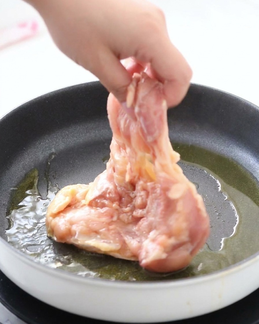 熱したフライパンに、鶏肉を皮目から入れて焼いている様子。