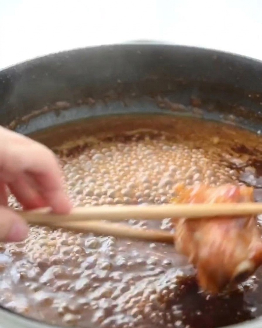 フライパンの中でタレが泡立ち、鶏肉に絡んでとろみがついている様子。
