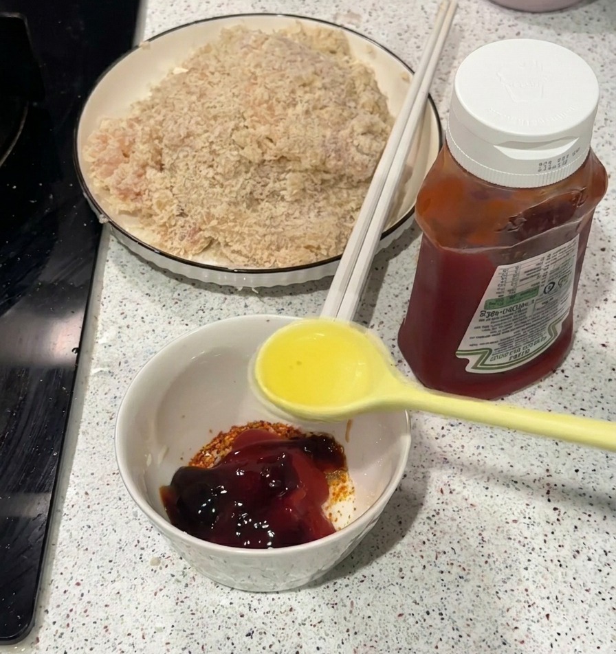 ケチャップやスパイスが入った小さな白いボウルに、熱した油を注いでいる様子