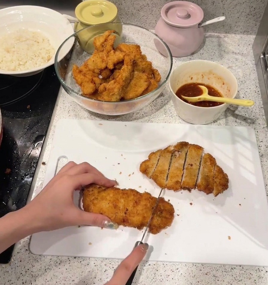 こんがりと揚がったサクサクのチキンカツを、白いまな板の上で切り分けている様子