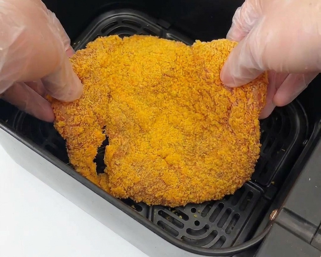 エアーフライヤーのバスケットに衣をつけた鶏肉を並べる様子