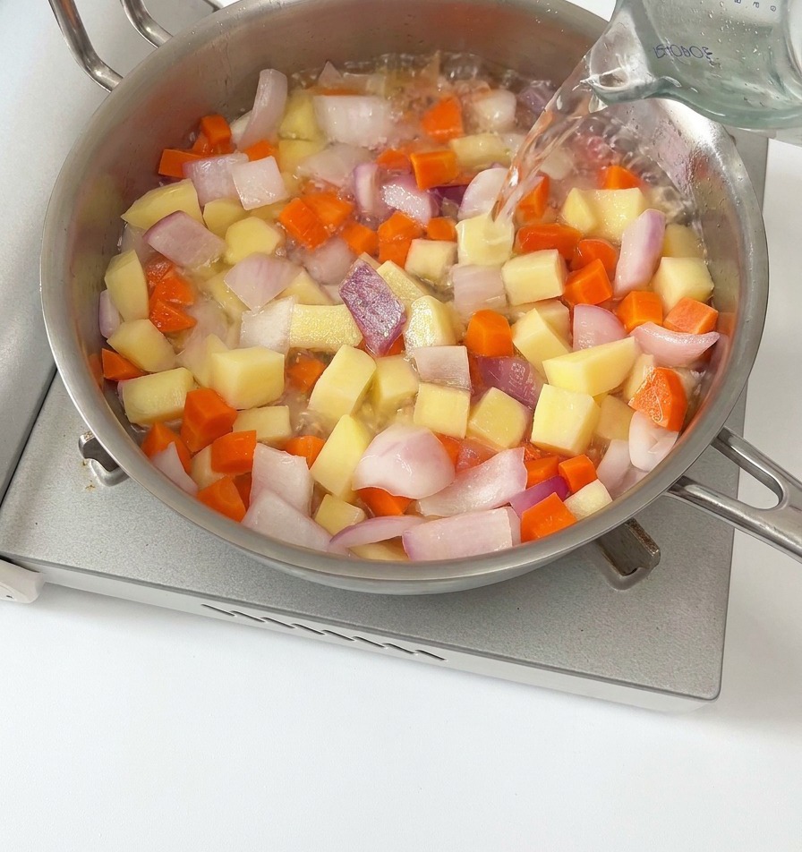 野菜が入った鍋に水を注いでいる様子