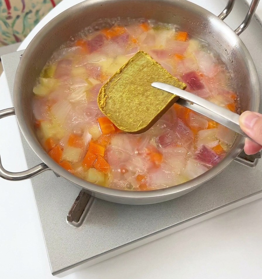 煮立った鍋にカレールーを割り入れる様子
