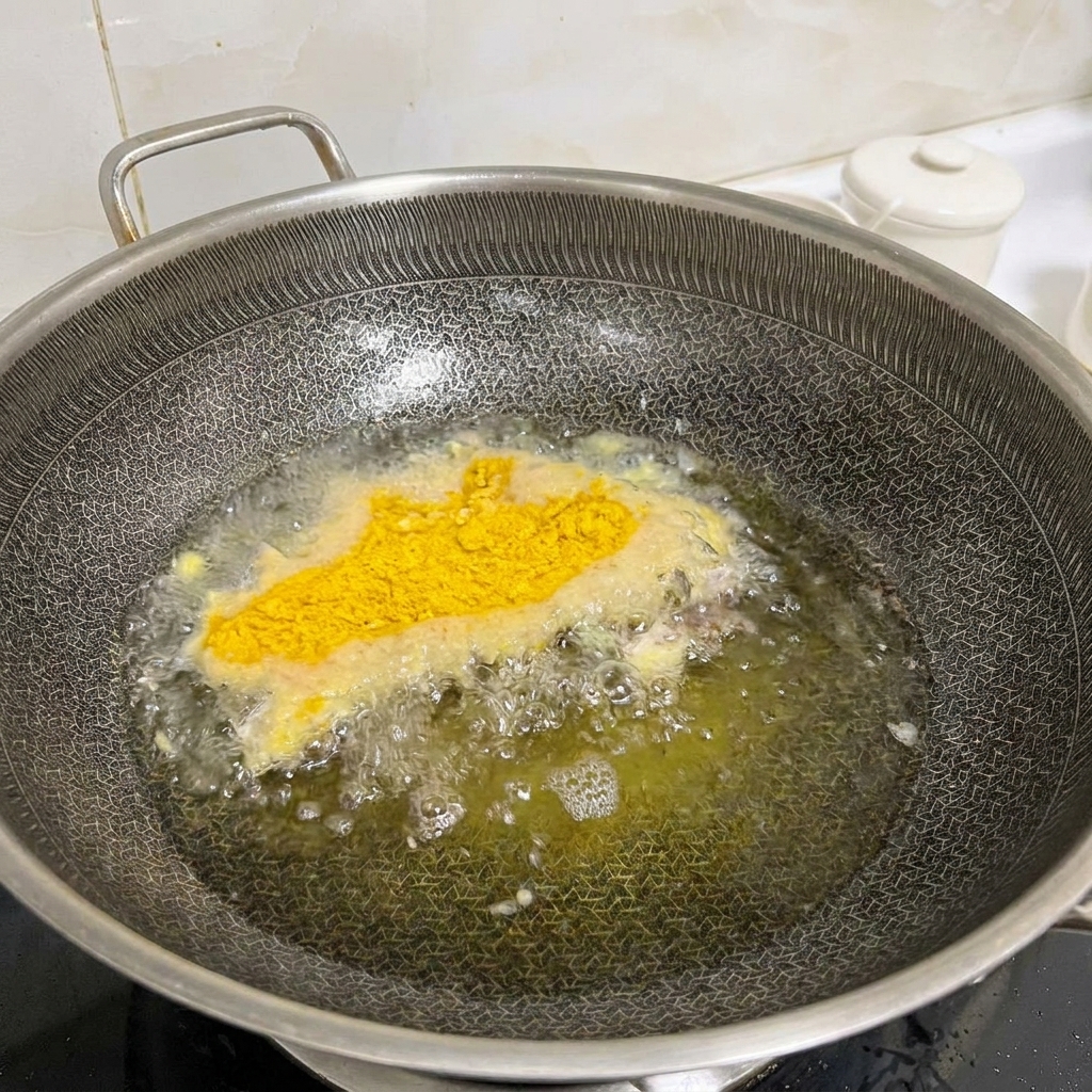 フライパンに少なめの油を引き、衣をつけた鶏肉をこんがりと揚げ焼きにしている様子。