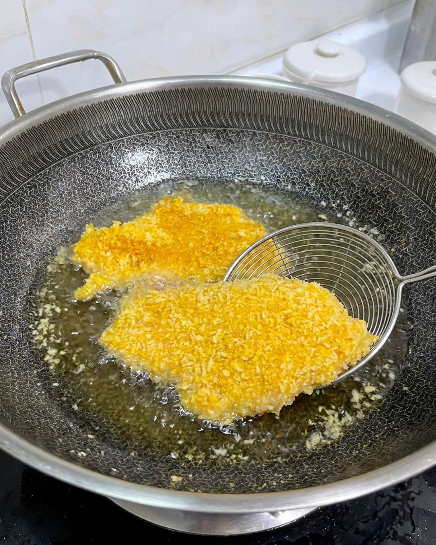 こんがりと焼けたチキンカツを裏返し、両面が均一に焼けているか確認している様子。
