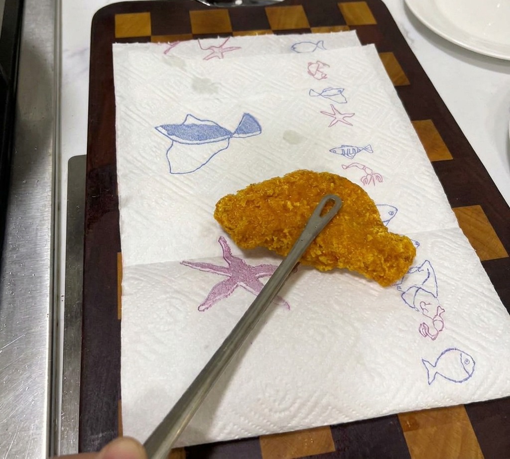 揚げたてのチキンカツをキッチンペーパーを敷いた皿に乗せて油を切っている様子。