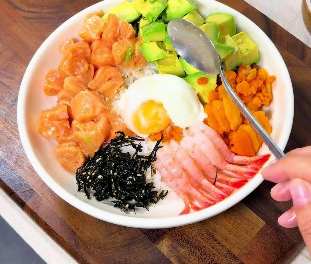 丼の中央に温泉卵を落とし、その上にいくらを添えている様子