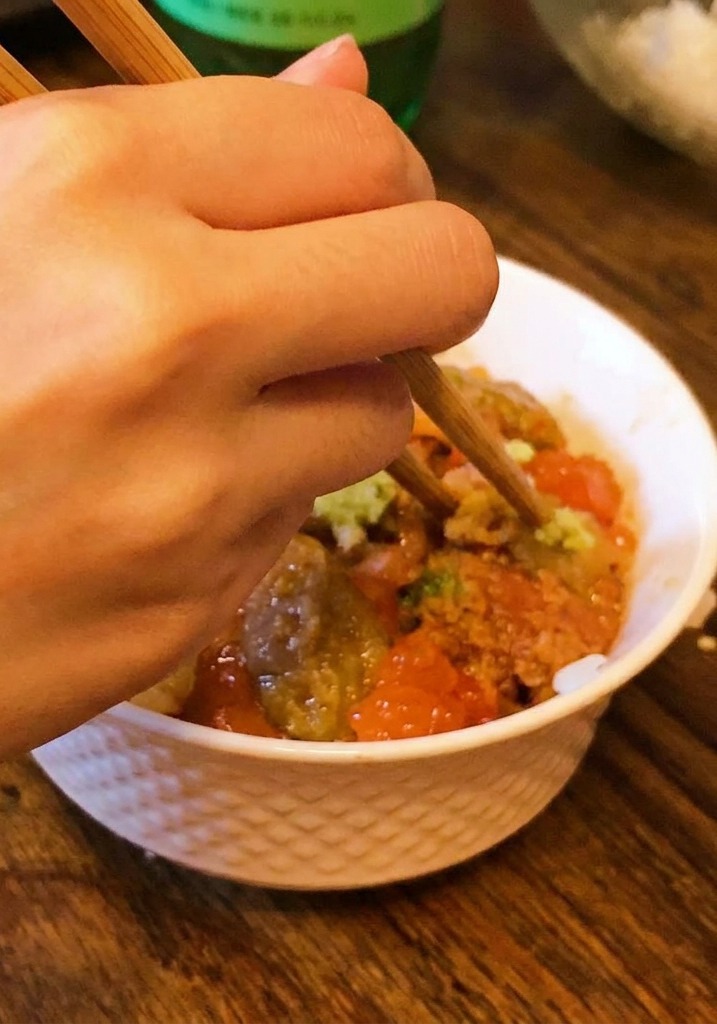 丼の中央に、箸で少量のわさびを盛り付けているアップ画像。