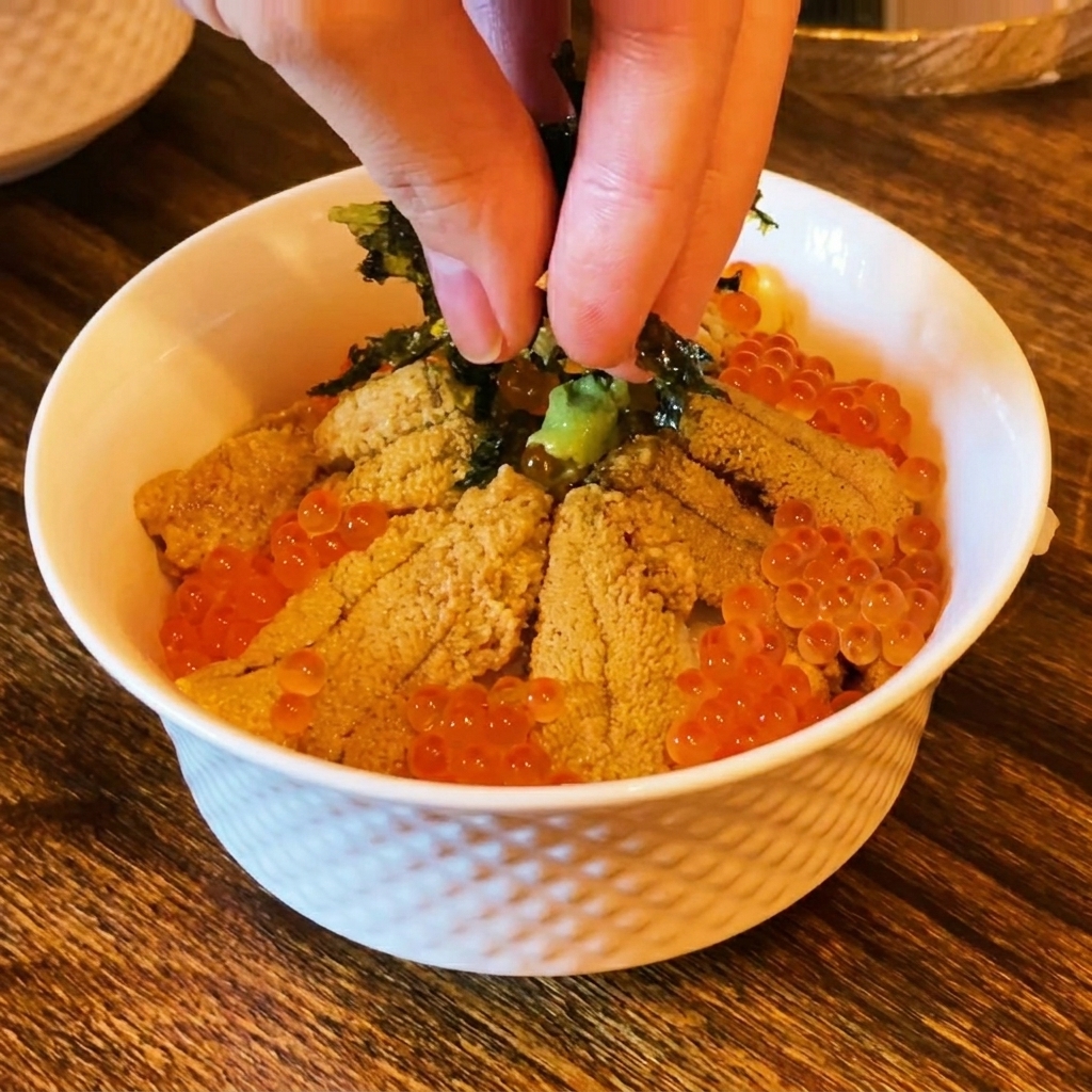 盛り付けが終わった丼の上に、指で刻み海苔をパラパラと振りかけている様子。